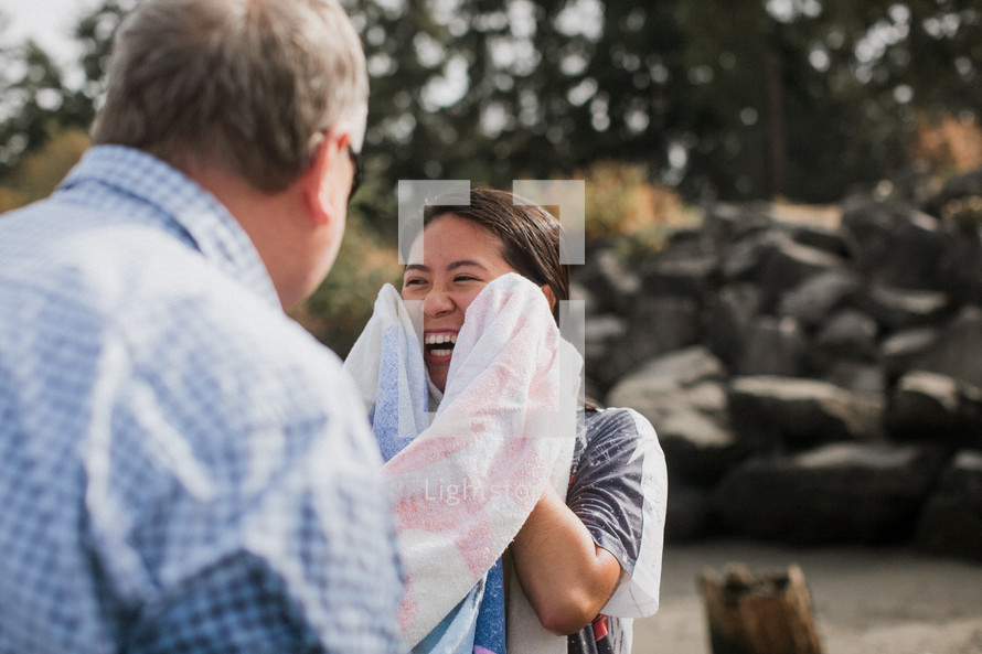 a woman drying off with a towel after a baptism in a river 