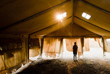 A boy standing alone in a tent 