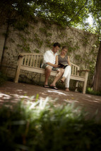 A young married couple sits on a bench reading God's word.