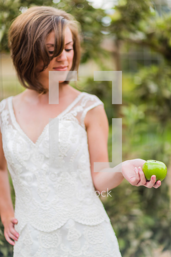 young woman girl in white dress holding a green apple