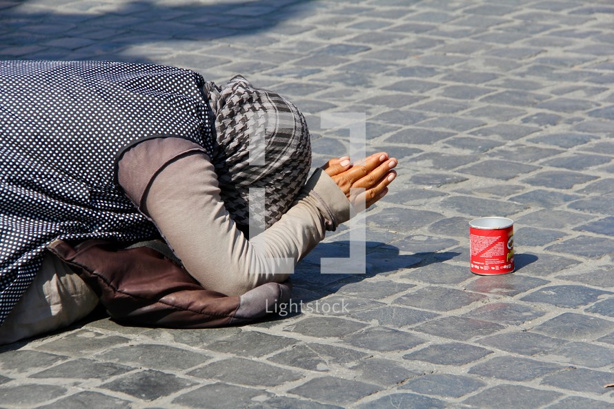 a woman kneeling and begging on the streets in Rome 