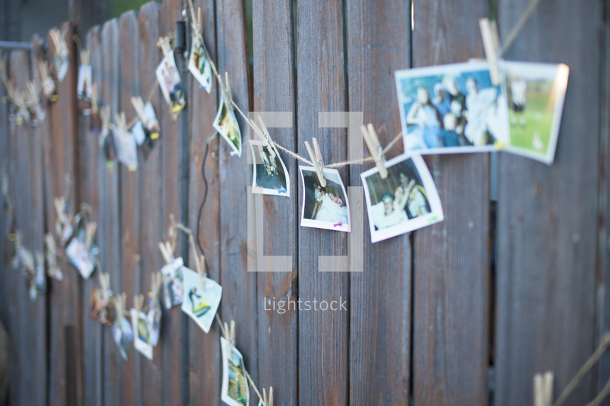 photos hanging on a line against a fence
