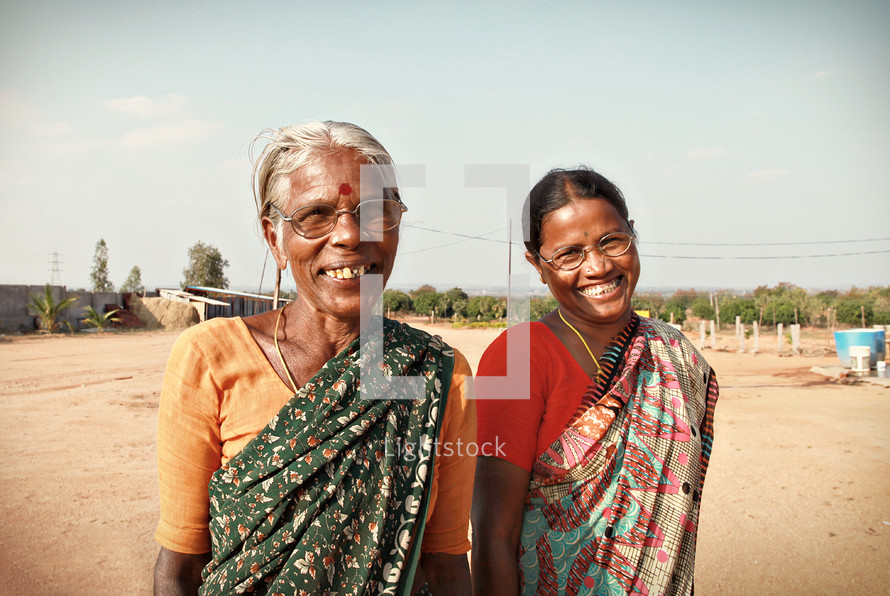 women smiling on a dirt road in India