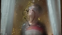 child drawing heart shape on window for Christmas 