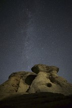 stars in the nights sky under a rock peak 
