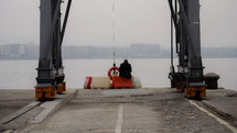 man sitting on a blockade on a dock 
