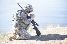 soldier with a rifle kneeling in prayer to God