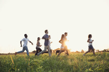 group of young adults running through tall grass