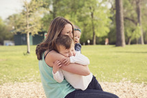 a mother hugging her children in the park 