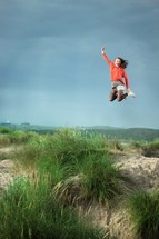 teen girl jumping for joy in a field