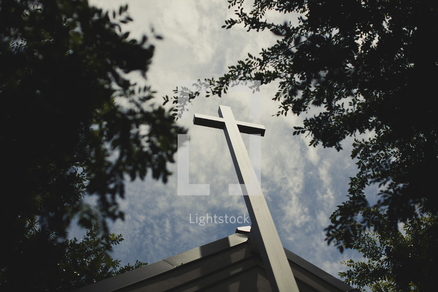 A cross positioned  on top of a church.