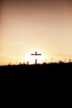 A silhouetted cross on the horizon at sunrise
