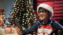 Little Boy using his Smartphone to show his Christmas tree 