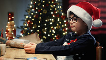 Kid preparing Christmas gifts for his friends on table