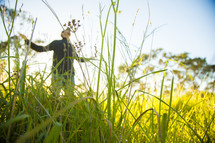 man with outstretched arms standing in tall grass 
