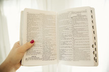 a woman holding out a Bible 