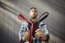Man holding Bible with jumper cables attached to corners.