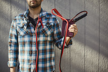 Man holding Bible with jumper cables attached from corners of Bible to his shirt collar.
