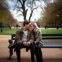 Young couple sitting on a bench in the park and looking at each other