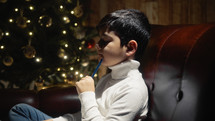 Little Child thinking and writing under Christmas tree 