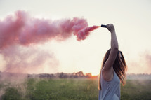 a young woman holding a pink smoke flare.