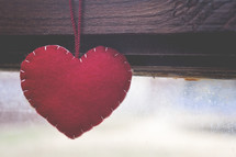 a felt heart ornament hanging in a window 