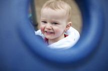 A baby seen through a playground window.