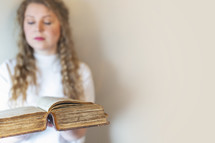a young woman holding large leather Bible