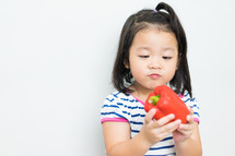 a little girl holding a pepper 