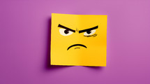 Mad face drawn on a yellow sticky note on a purple background.