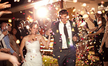 Bride and groom leaving wedding ceremony running in confetti