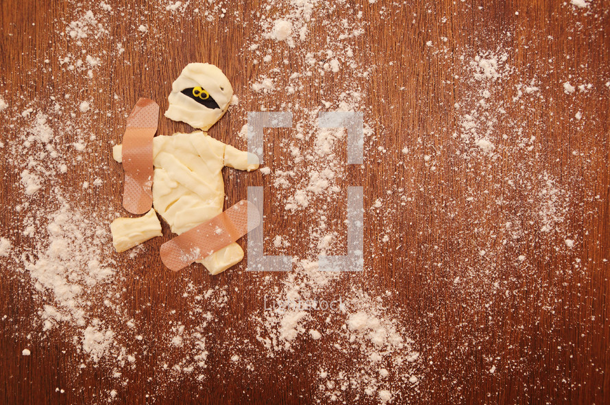 A broken Halloween mummy cookie mended with band-aids.
