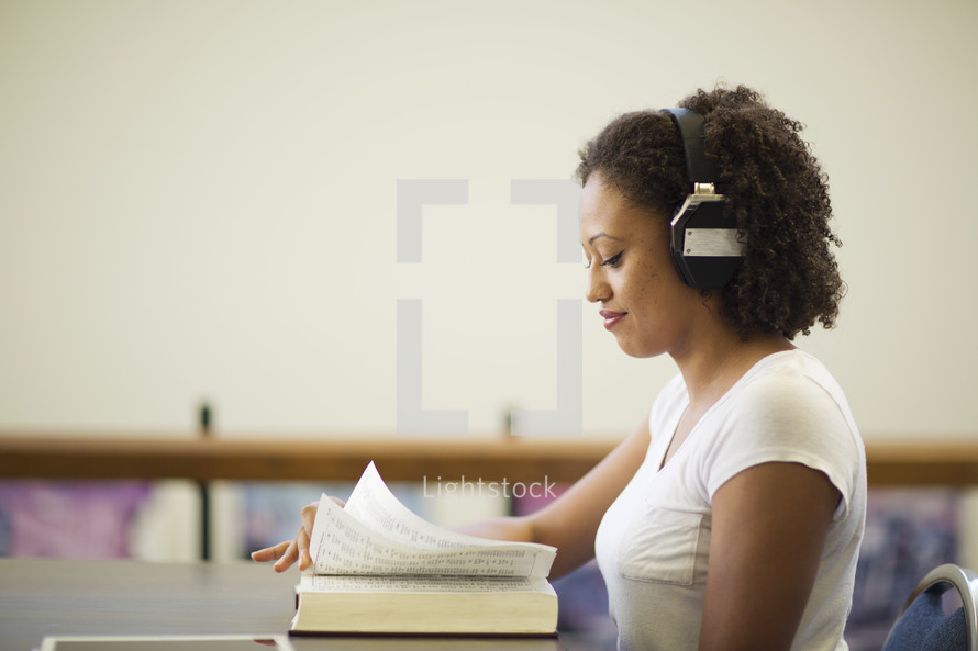 a woman reading and listening to headphones 