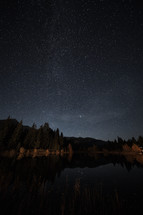 stars in the night sky over a mountain lake 