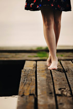 A girl walks on a wooden bridge to the lake. The bridge on the lake. Beautiful barefoot