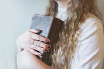 a young woman holding a well worn leather Bible