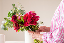 a senior woman arranging flowers in a vase 