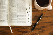pen, Bible, and coffee mug on a table 