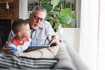 a grandfather reading a book to his grandson 