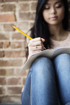 A young woman writing in a journal.