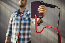 Man holding Bible with jumper cables attached.