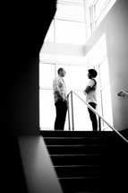 man and woman standing at the top of steps talking 