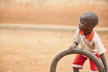 A young boy playing with a tire.