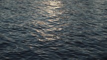Water ripples at sunset, sun shining on water, river, lake, sea, ocean surface blue water, dark water, liquid moving 4K outdoors nature background texture