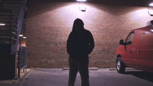 a young man in a parking lot at night looking down at the ground 