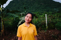 a smiling young woman in a clearing in the jungle 