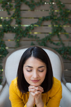 a woman sitting in a chair outdoors with praying hands 