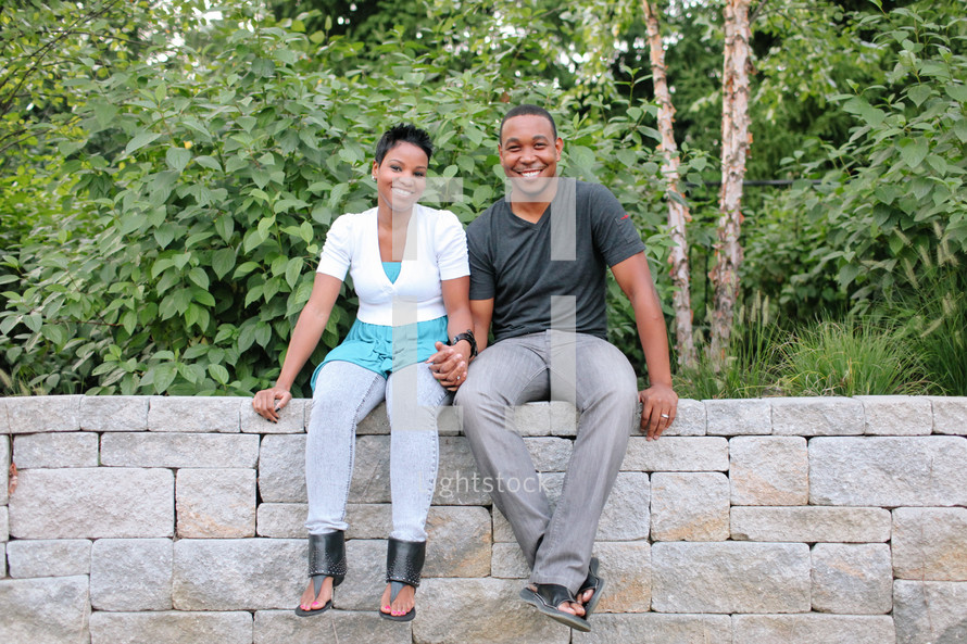 couple sitting on a stone wall holding hands
