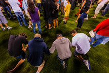 Young men in prayer holding hands crusade accept Christ salvation kneeling one knee 