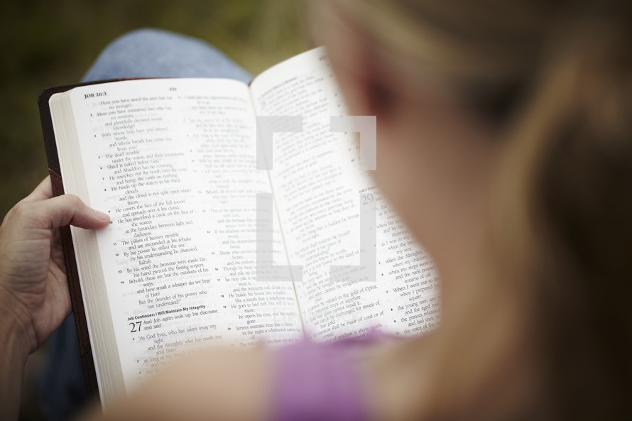 An over the shoulder view of a woman reading her Bible